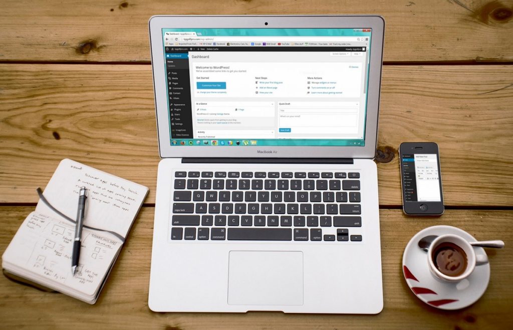 Laptop on a table next to a phone and coffee